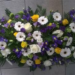 Casket spray in whites, yellows and purples