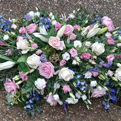 Pretty casket spray in pink, lilac, blue and white